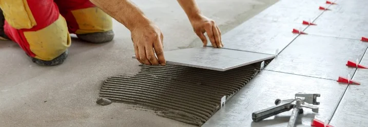 Person verlegt Fliesen mit Fliesenzange